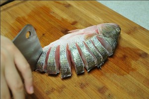 將鱸魚(yú)清洗干凈，從脊椎處切斷至腹部，腹部保留1cm左右不要切斷。